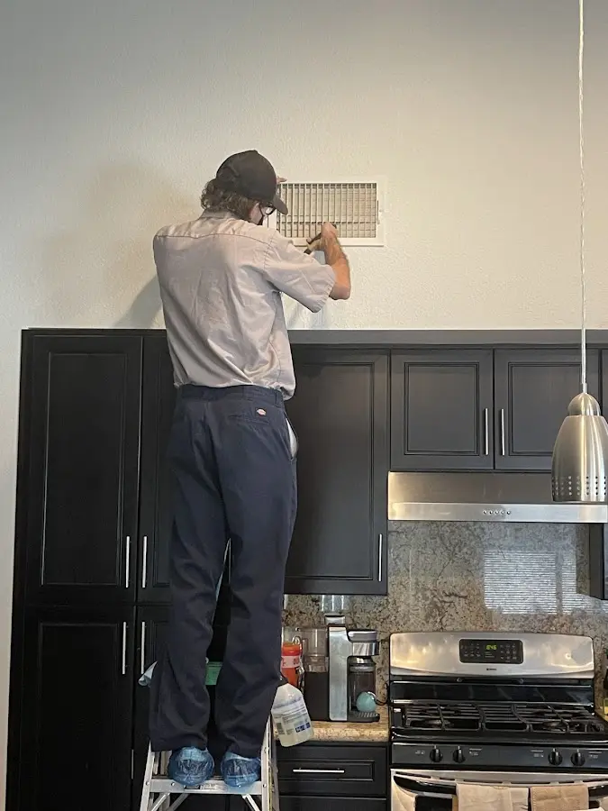 Technician inspecting an air vent during HVAC service in Vinita